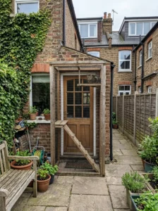 Small DIY catio attached to a terrace house with shelves and a ramp