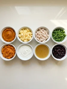 Eight homemade dog food toppers including pumpkin, cooked chicken, egg, green beans, and yogurt.